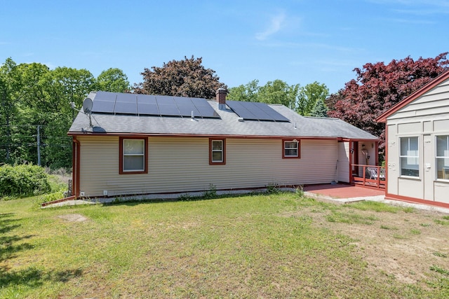 rear view of house featuring solar panels, a yard, and a patio