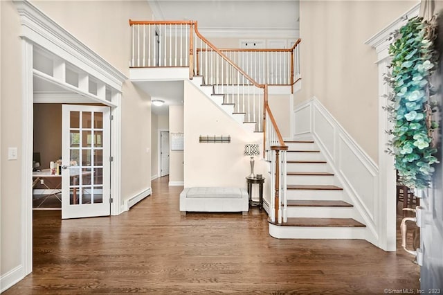 stairway with a baseboard radiator, french doors, hardwood / wood-style floors, and ornamental molding