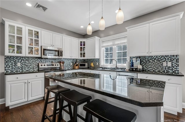 kitchen with a kitchen island, white cabinetry, a kitchen breakfast bar, and stainless steel appliances