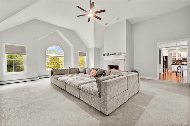 living room with a brick fireplace, baseboard heating, light carpet, ceiling fan, and lofted ceiling