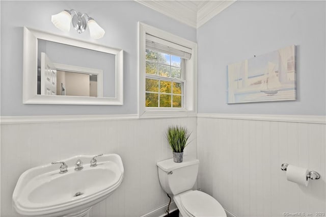 bathroom featuring sink, toilet, crown molding, and wooden walls