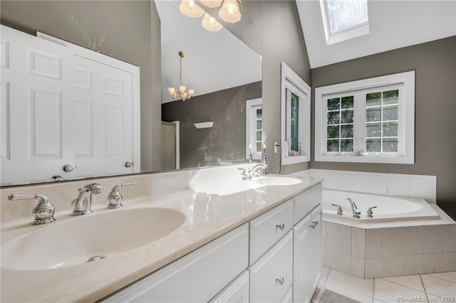 bathroom with tile patterned flooring, tiled tub, vaulted ceiling with skylight, vanity, and a chandelier