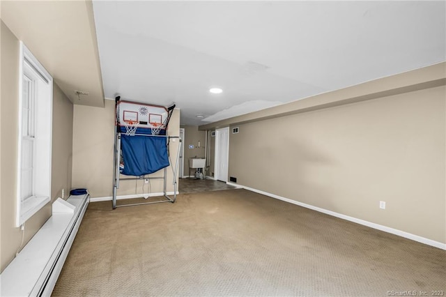 basement with sink, a baseboard heating unit, and carpet floors