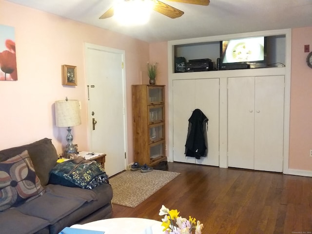 living room featuring dark wood-type flooring and ceiling fan