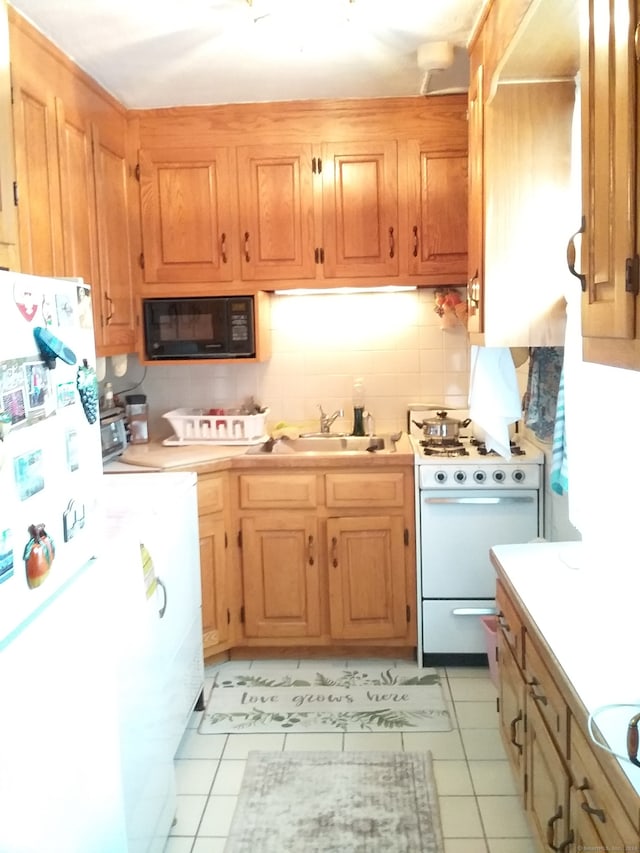 kitchen with washer / dryer, tasteful backsplash, sink, white appliances, and light tile floors