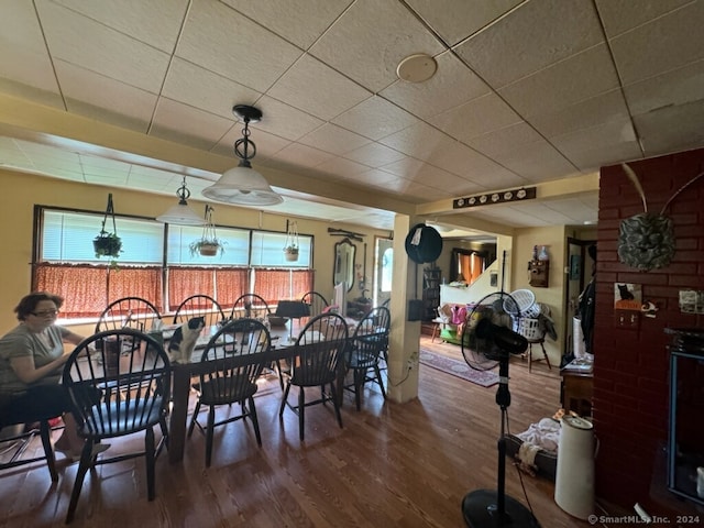 dining space featuring a healthy amount of sunlight, brick wall, and a drop ceiling