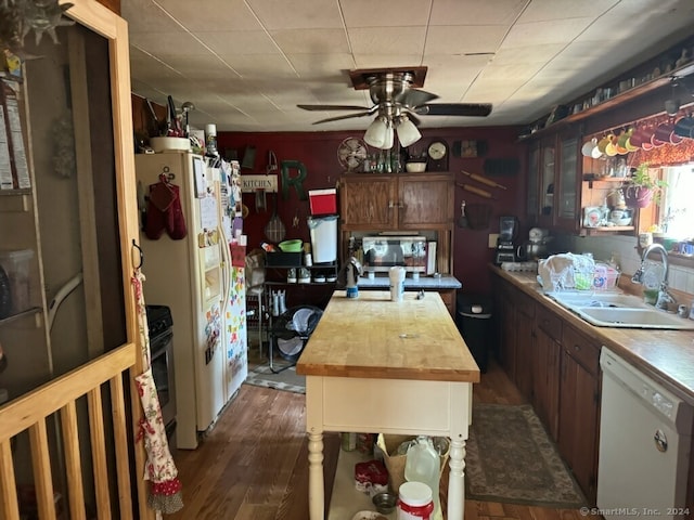 kitchen with wood counters, a kitchen island, dark wood-type flooring, sink, and white appliances