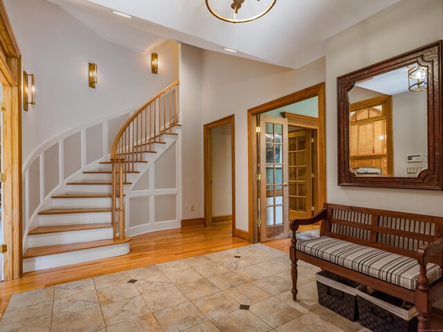 entryway featuring a high ceiling, light wood-type flooring, french doors, and an inviting chandelier