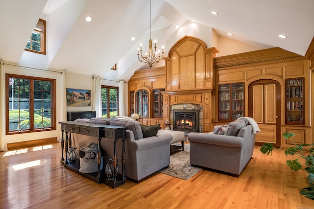 living room with high vaulted ceiling, an inviting chandelier, and light wood-type flooring