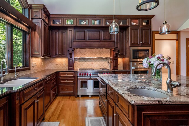 kitchen with stainless steel appliances, hanging light fixtures, sink, and light stone counters