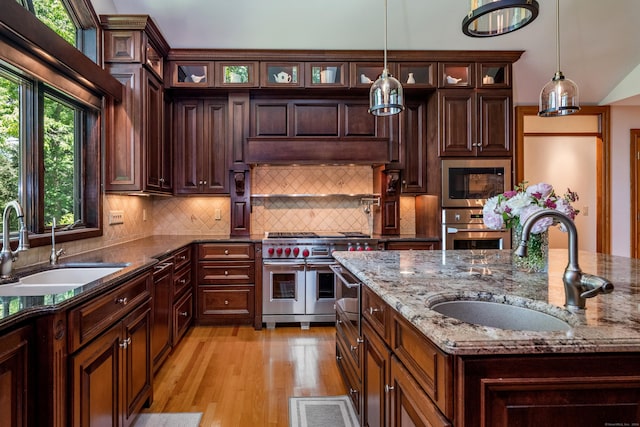 kitchen featuring pendant lighting, sink, stainless steel appliances, and light stone countertops