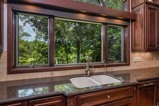 kitchen featuring decorative backsplash, dark stone countertops, and sink