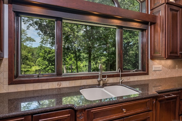 kitchen with tasteful backsplash, dark stone counters, sink, and a wealth of natural light