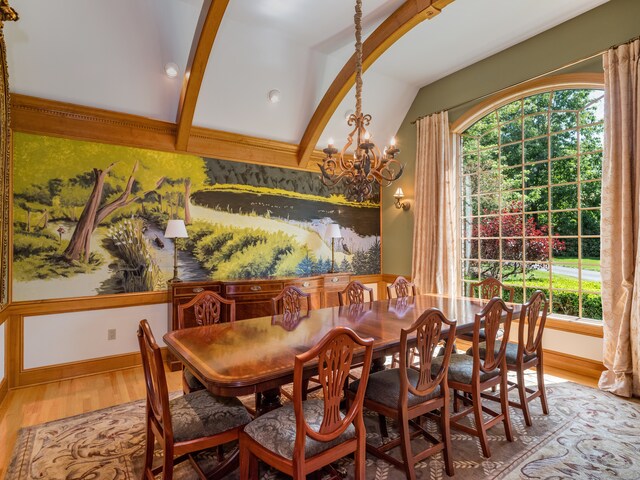 dining space featuring a notable chandelier, lofted ceiling with beams, a healthy amount of sunlight, and hardwood / wood-style flooring