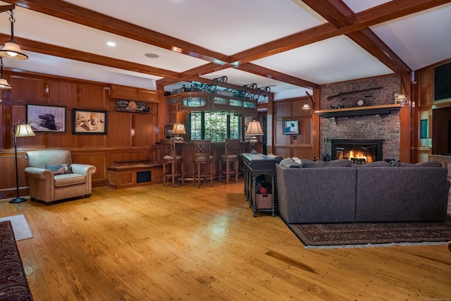 living room with a brick fireplace, beam ceiling, light hardwood / wood-style floors, and wood walls