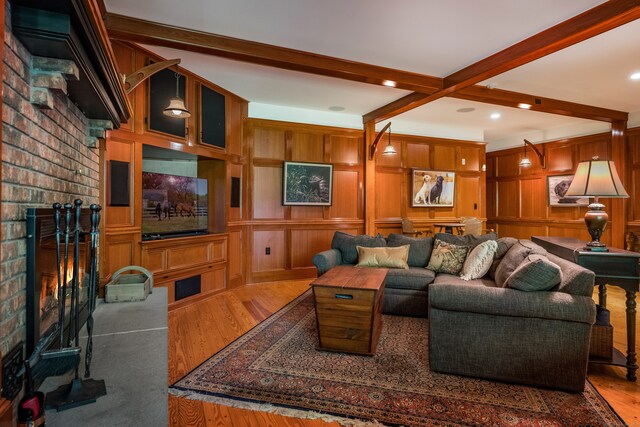 living room with beamed ceiling, wood walls, a fireplace, and hardwood / wood-style floors