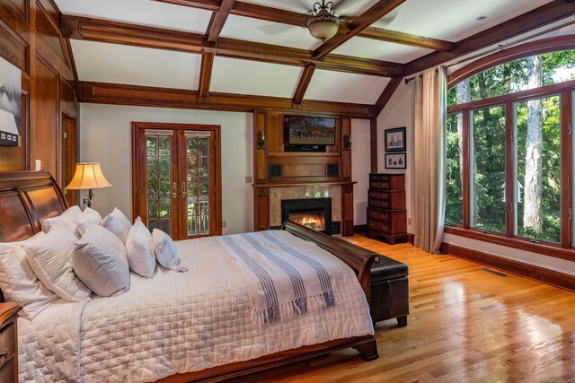 bedroom with light wood-type flooring, multiple windows, ceiling fan, and beamed ceiling