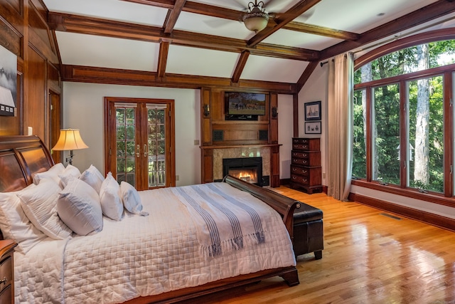 bedroom with lofted ceiling with beams, light wood-type flooring, ceiling fan, and french doors