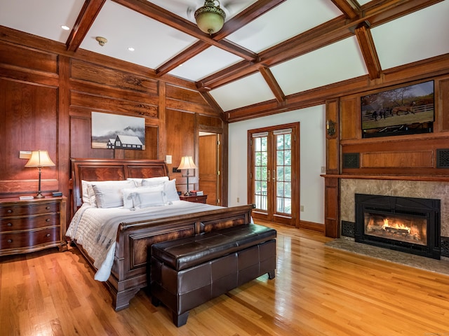 bedroom featuring a tile fireplace, wooden walls, ceiling fan, and light wood-type flooring