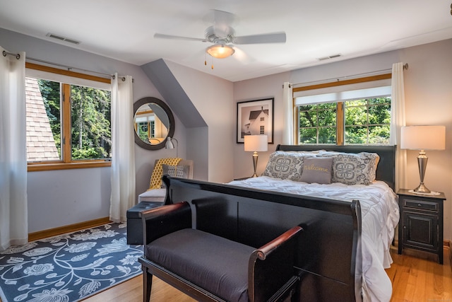 bedroom featuring ceiling fan, hardwood / wood-style floors, and multiple windows