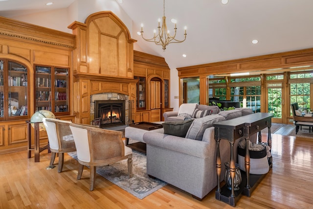 living room with a stone fireplace, light hardwood / wood-style flooring, high vaulted ceiling, and wood walls