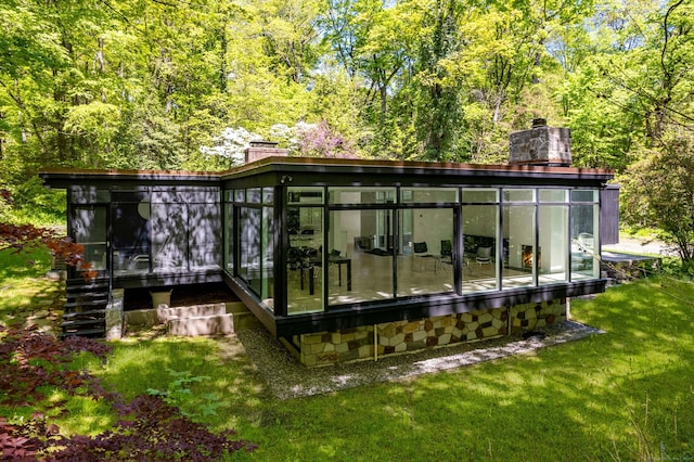 back of property with a sunroom and a lawn