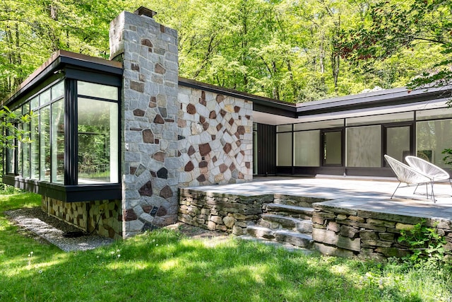 rear view of property featuring a sunroom and a patio area