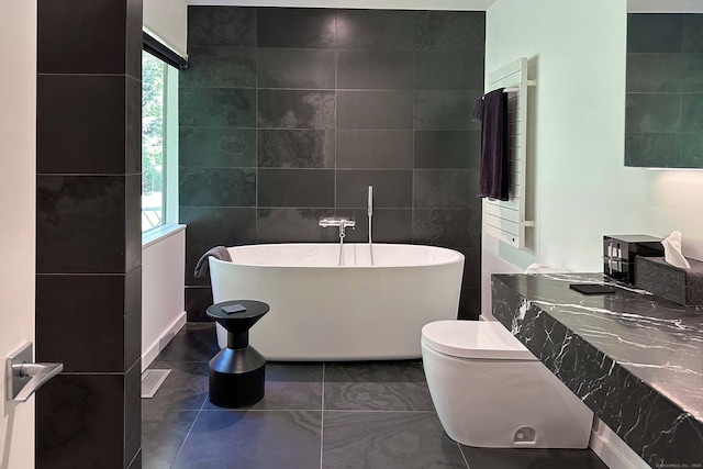 bathroom featuring tile walls, toilet, and a bath