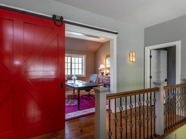 corridor with a barn door and dark hardwood / wood-style floors