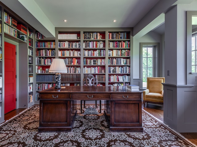 office with a wealth of natural light, built in features, and dark hardwood / wood-style flooring