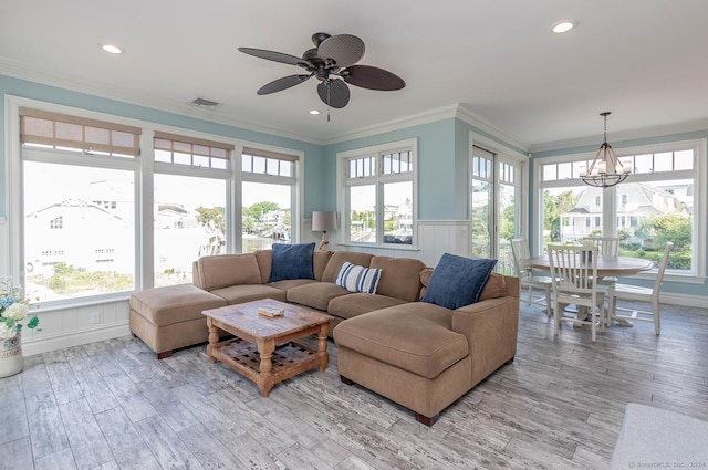 living room featuring hardwood / wood-style floors, ceiling fan with notable chandelier, a healthy amount of sunlight, and crown molding