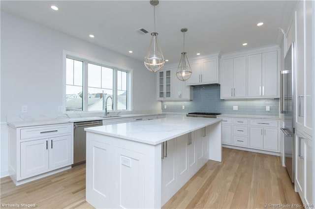 kitchen featuring stainless steel appliances, sink, white cabinetry, light hardwood / wood-style floors, and a kitchen island