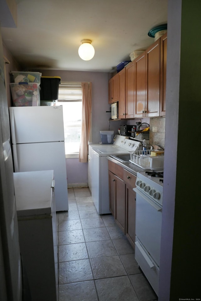 kitchen featuring white appliances, washing machine and clothes dryer, and light countertops