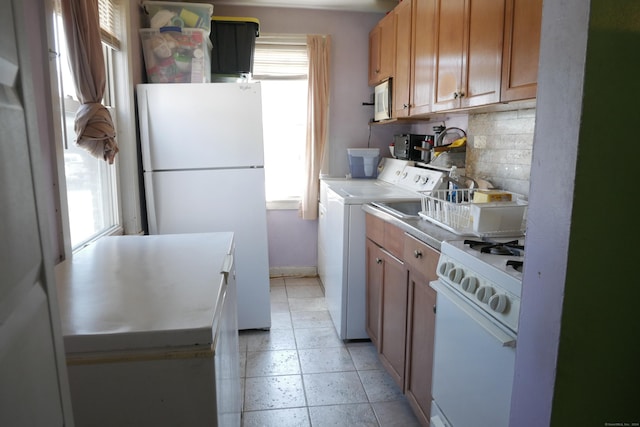 kitchen featuring tasteful backsplash, white appliances, independent washer and dryer, light countertops, and baseboards