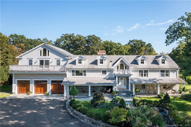 shingle-style home featuring aphalt driveway, a balcony, and an attached garage