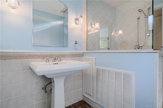 bathroom with a tile shower and tile walls