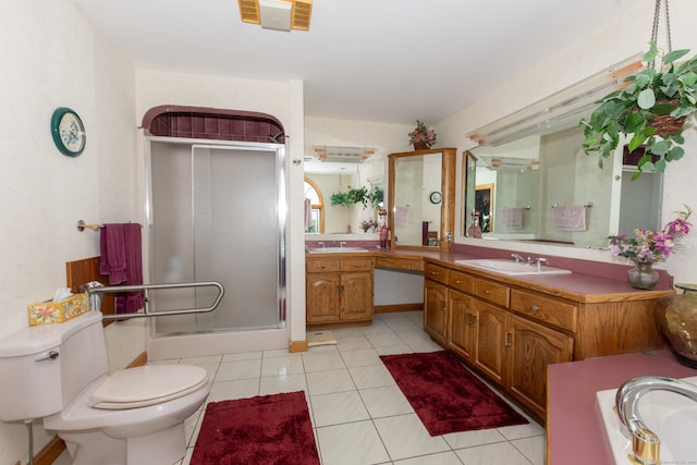 bathroom featuring vanity, toilet, tile floors, and a shower with door