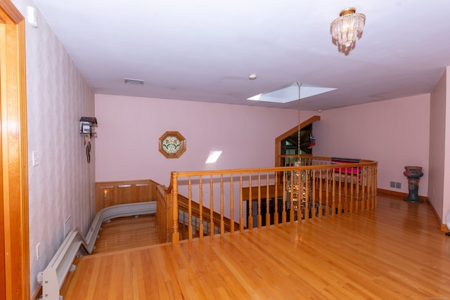 hallway with a notable chandelier, a skylight, and hardwood / wood-style floors