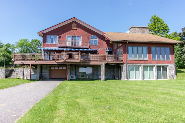 rear view of house with a garage, a lawn, and a wooden deck