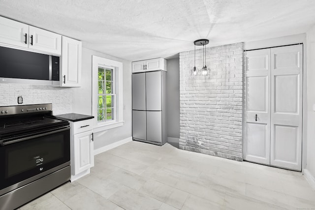 kitchen with appliances with stainless steel finishes, decorative light fixtures, white cabinetry, a textured ceiling, and decorative backsplash