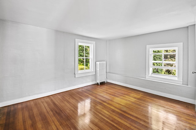 unfurnished room featuring radiator heating unit and hardwood / wood-style floors