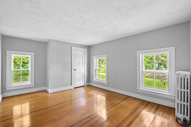 spare room featuring radiator and wood-type flooring