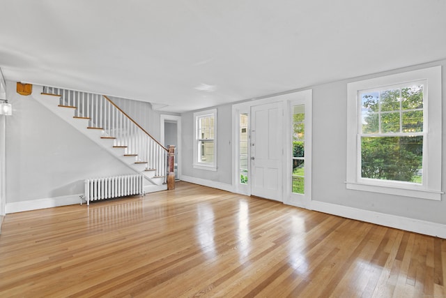 foyer entrance with radiator heating unit and light hardwood / wood-style flooring