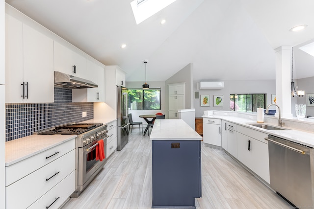 kitchen with appliances with stainless steel finishes, hanging light fixtures, sink, and a center island