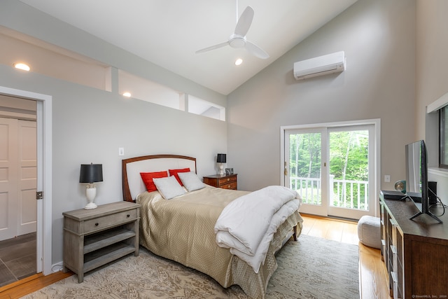 bedroom featuring light hardwood / wood-style floors, access to exterior, high vaulted ceiling, a wall mounted air conditioner, and ceiling fan