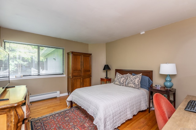 bedroom with hardwood / wood-style floors and baseboard heating