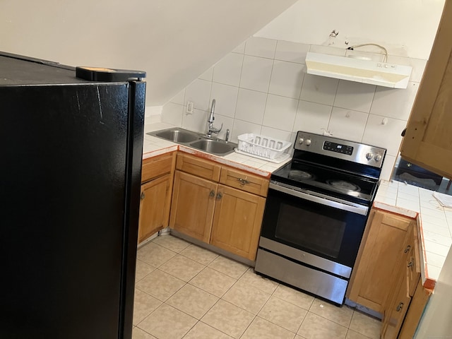 kitchen with sink, tile counters, stainless steel range with electric cooktop, and black fridge