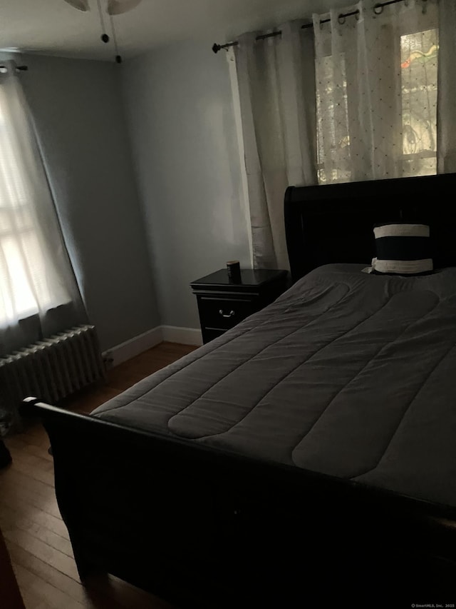 bedroom with hardwood / wood-style flooring and radiator heating unit