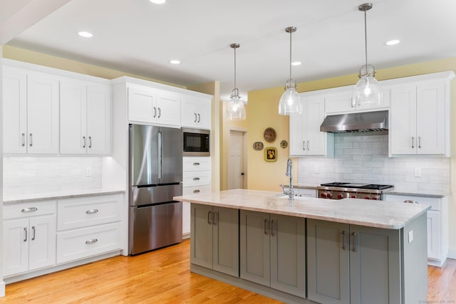 kitchen featuring pendant lighting, a kitchen island with sink, light hardwood / wood-style floors, white cabinetry, and stainless steel appliances