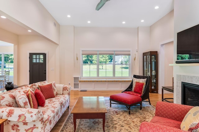 living room featuring a towering ceiling, a fireplace, and light hardwood / wood-style flooring